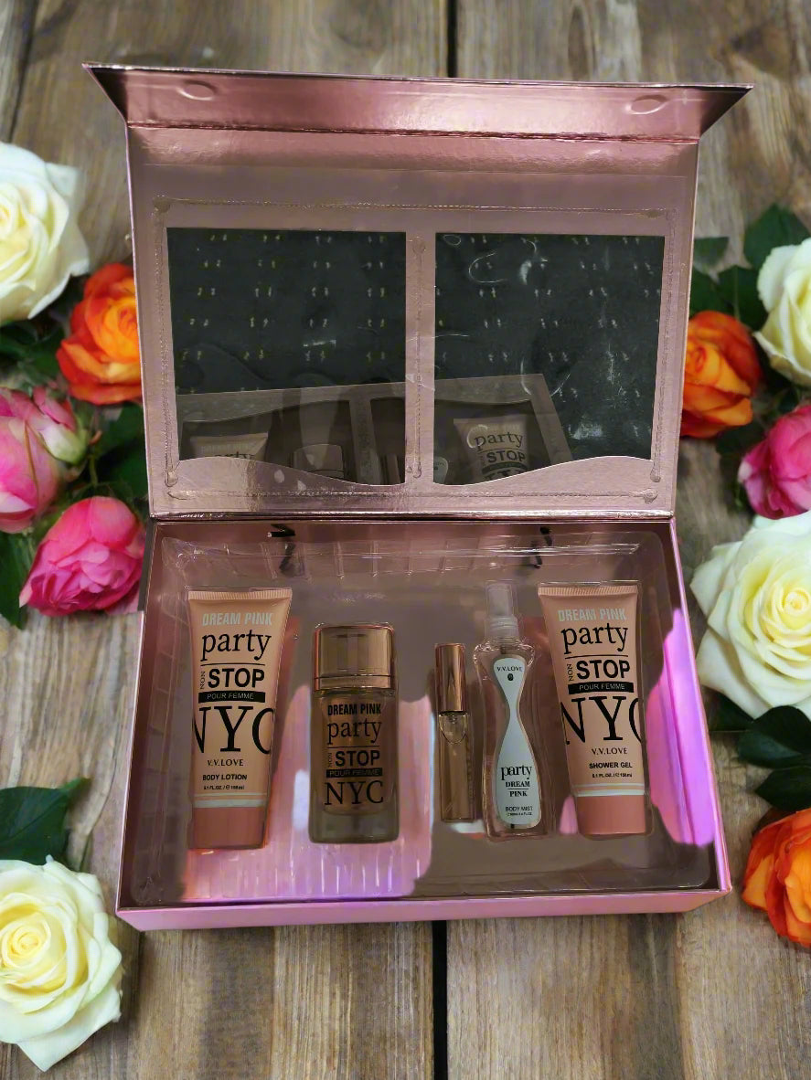 Set of cosmetic products including lip balms and a brush in a rose gold case on a textured black surface.