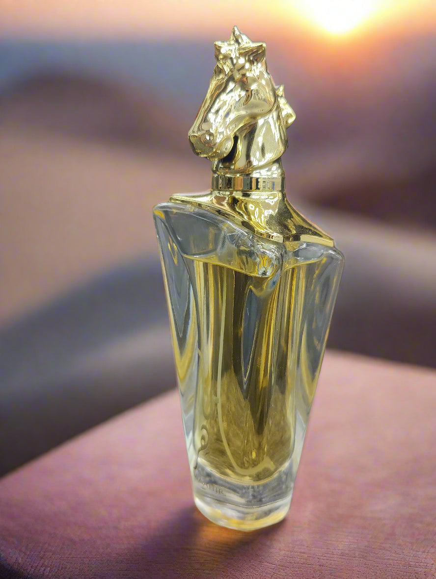 Perfume bottle with gold horse-shaped cap on a textured surface