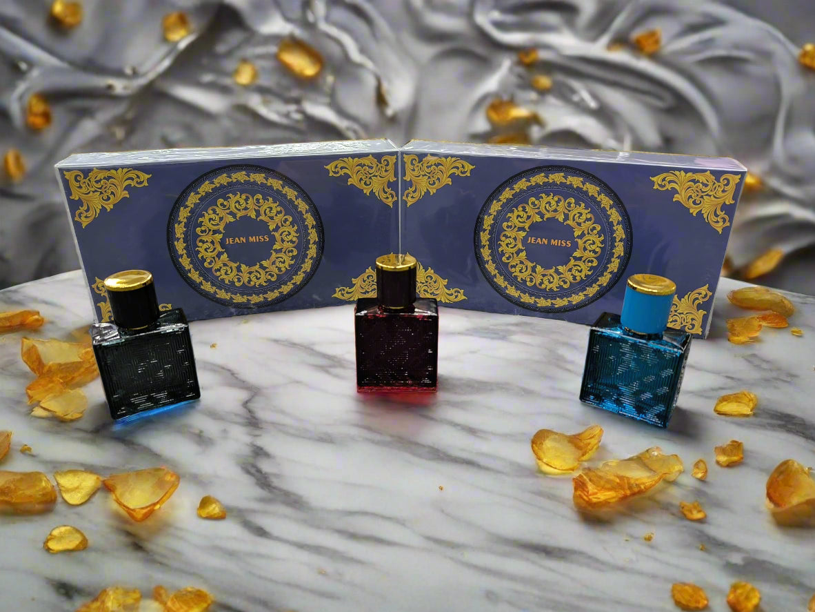 Three perfume bottles with decorative boxes on a textured surface