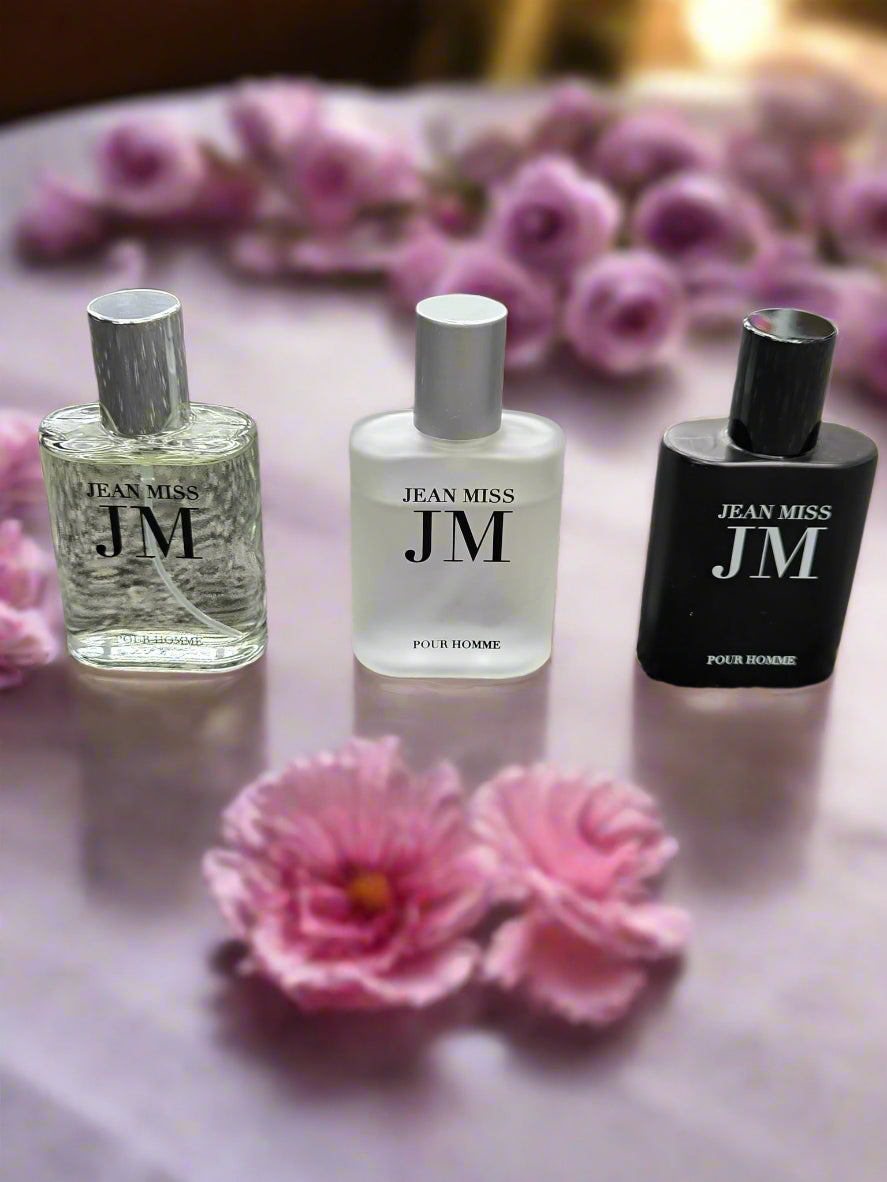 Three bottles of Jean Miss JM perfume on a textured surface
