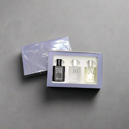 Set of three perfume bottles in a box on a textured gray background