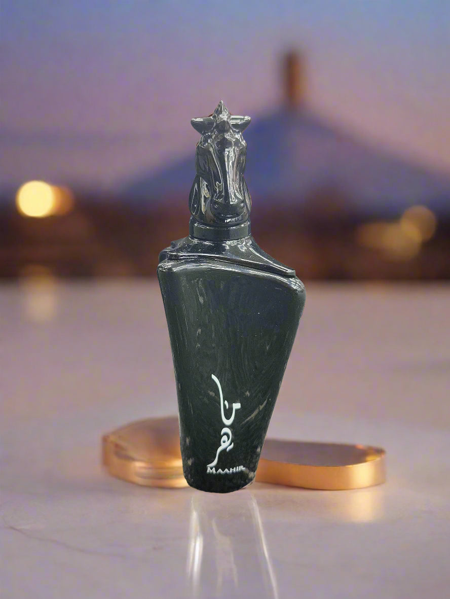 Black perfume bottle with decorative cap on a textured surface, with 'MAHER' branding.