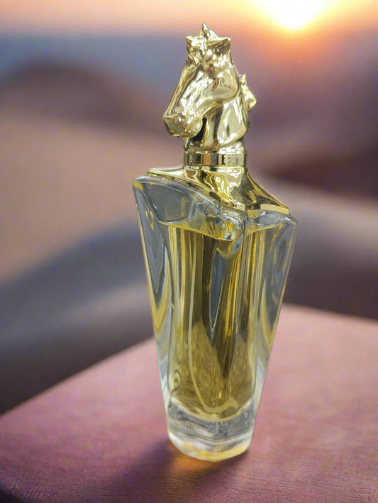 Perfume bottle with gold horse-shaped cap on a textured surface