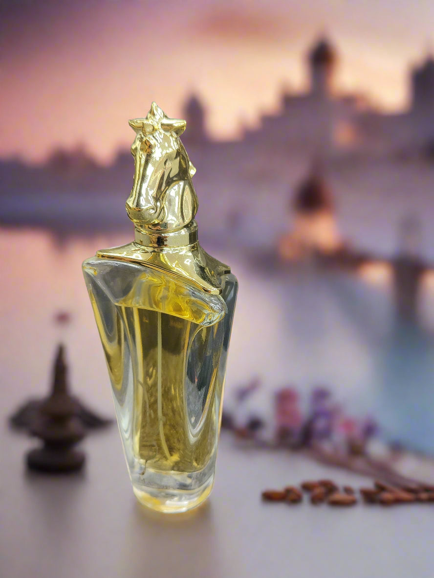 Gold and clear perfume bottle with horse head design on a textured surface.