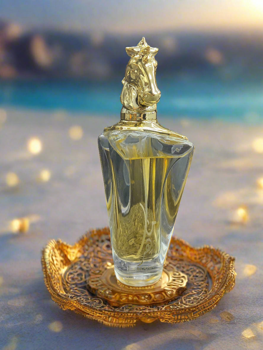 Perfume bottle with gold cap and clear body on a textured surface, with 'MAAHR' branding in the background.