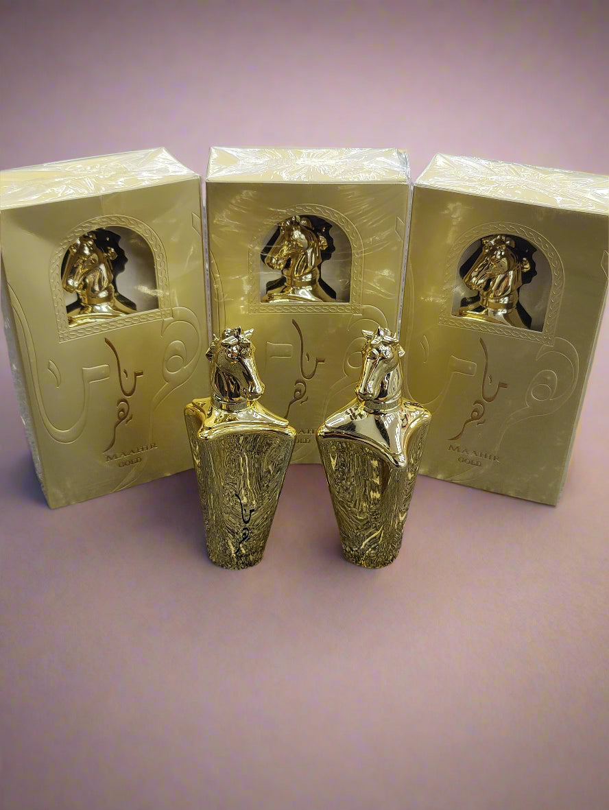 Two gold perfume bottles with their boxes on a textured surface