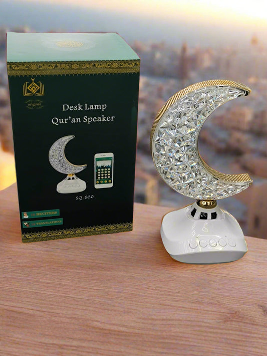 Desk lamp with crystal moon design next to its packaging on a textured surface