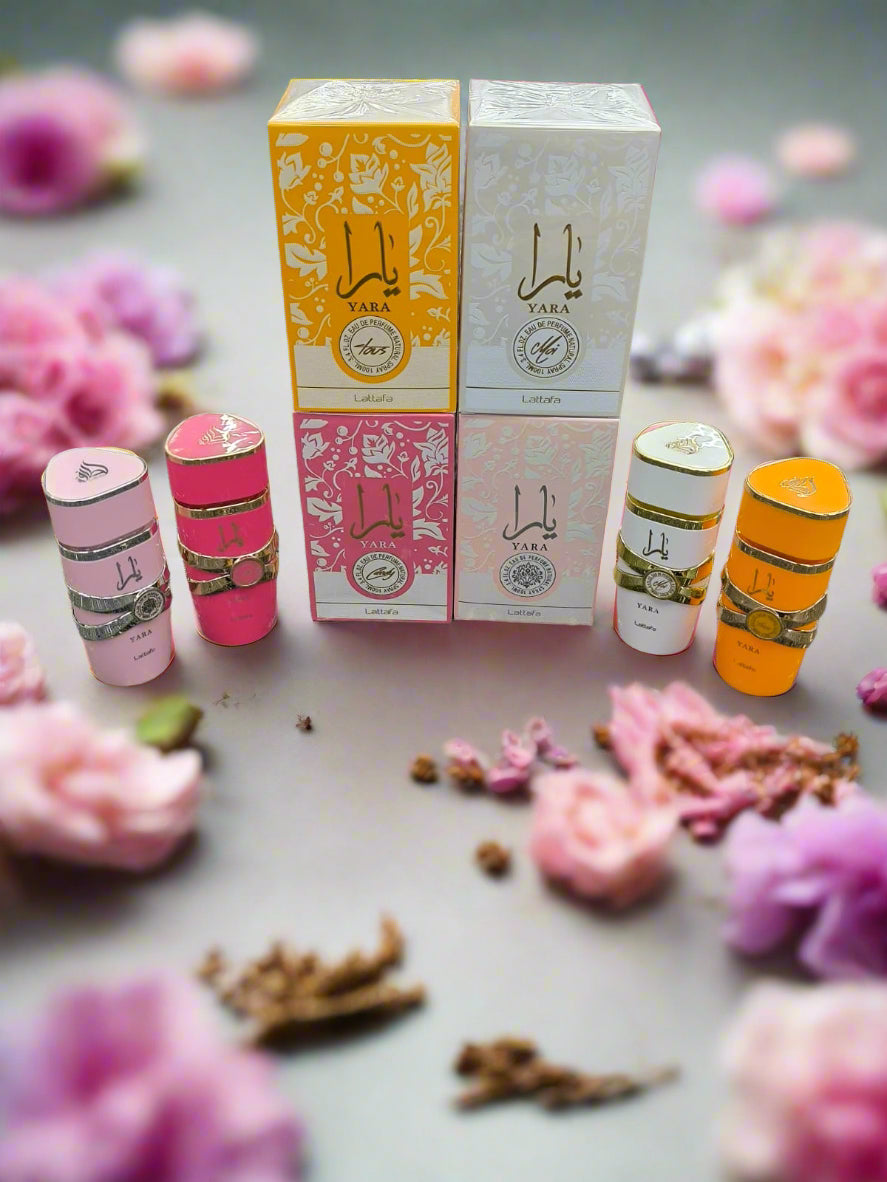 Three Yara perfume bottles and boxes on a textured surface
