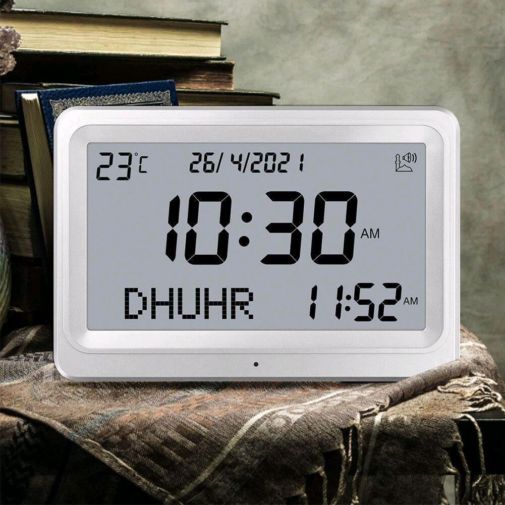 Digital clock displaying time and date on a textured surface with books in the background